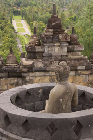 Back view of buddha statue in stupa at Borobudur buddhist temple landscape, Java, Indonesia. Candi...