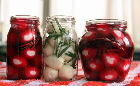 Marinated quail eggs in jars. Preparing quail eggs delicacy for Easter, with beetroot, vinegar, rosemary and pepperの写真素材