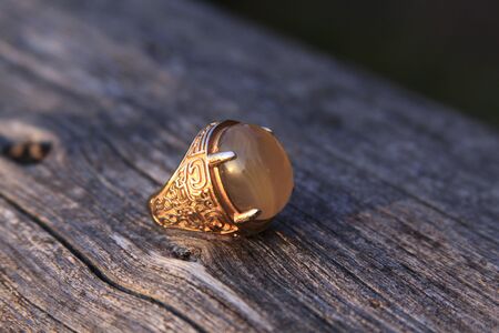 Muslim men aqeeq mood ring with yellow chalcedony agate gemstone on wood. Islamic males from Arabic cultures wear akik or aqiq rings on their handsの写真素材
