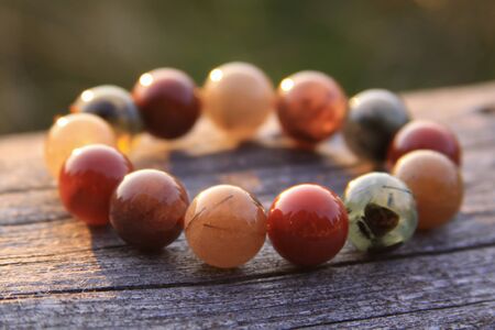 Bracelet jewelry made of different types of round gemstone beads, including translucent red, green, orange, yellow and white. Some of them are rutilated and tourmalinated quartz.の写真素材