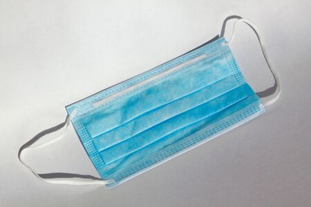 Single isolated blue medical mask for virus protection on white background. The surgical mask is a...