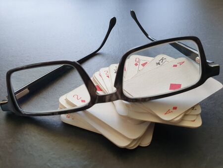 Glasses and deck of poker cards on table as symbol for gambling. Indoor home isolation activity, as social distancing quarantine measures restrict going outside during Coronavirus pandemic lockdown.の写真素材