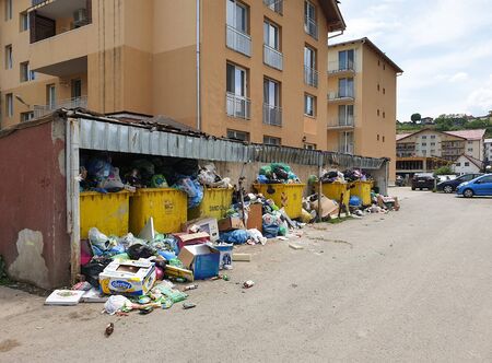 Messy pollution in garbage dump area spills in the streets of Floresti, Cluj, Romania. Trash accumulation in the street from filled yellow bins in apartment buildings neighborhood. Environment problemの写真素材