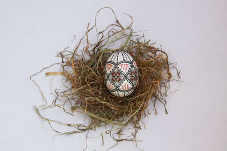 Isolated traditional handmade Easter eggs vintage decoration on hay. Seasonal motif on hand wax painting technique from Bucovina, Romania used to decorate Easter eggs in Moldova and Eastern Europe.の写真素材