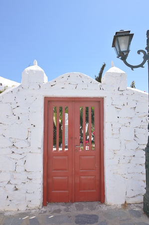 Red Gate Of The Panagia Tourliani Monastery In Ano Mera On The Island Of Mykonos. Architecture Landscapes Travels Cruises. July 3, 2018. Ano Mera, Island of Mikonos Greece.のeditorial素材