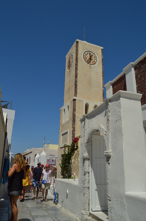 Upper Facade Of The Buildings Of The Beautiful Main Street Of Oia Where There Is A Beautiful Clock On The Island Of Santorini. Architecture, landscapes, travel, cruises. July 7, 2018. Island of Santorini, Thera. Greece.のeditorial素材