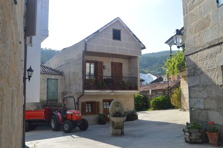 Tractor And Stone Fountain Next To A Stone House In The Beautiful Village Of Combarrro. Nature, Architecture, History, Street Photography. August 19, 2014. Combarro, Pontevedra, Galicia, Spain.のeditorial素材