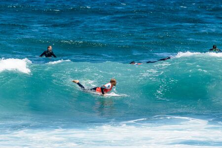 Group Of Surfers Waiting On Top Of The Table To Break Waves On Las Americas Beach. April 11, 2019. Santa Cruz De Tenerife Spain Africa. Travel Tourism Street Photography.の写真素材