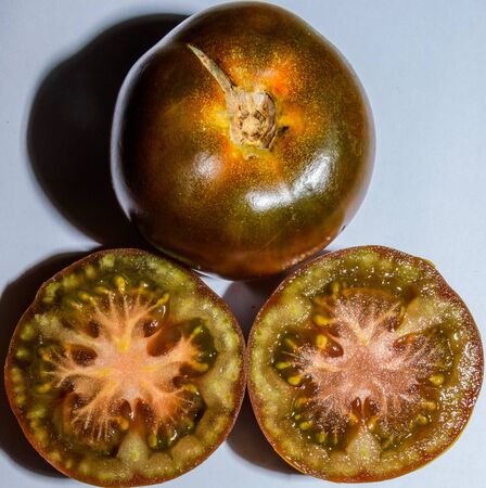 Fresh Pair Of Kumato Tomatoes One Of Them Open In Half On White Backgroundの写真素材