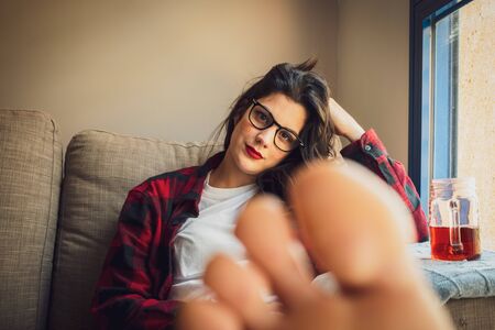 Young woman drinking tea on her sofa