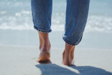 Close-up of feet walking on the beachの写真素材