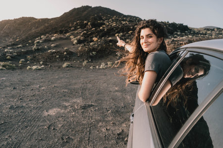Young woman admiring amazing volcanic landscape from her car at sunsetの写真素材