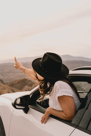 Young woman admiring a beautiful desert landscape from her car at sunset
