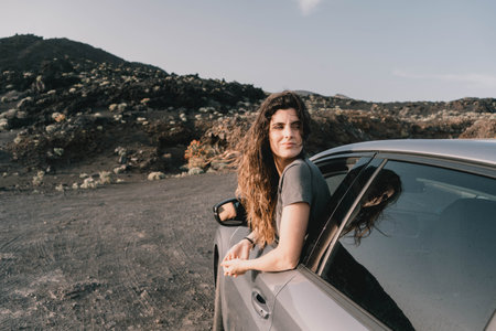 Young woman admiring amazing volcanic landscape from her car at sunsetの写真素材