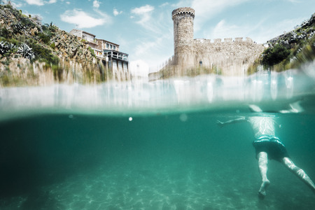 Vista desde el agua de un hombre nadando frente a el Castillo de Tossa de Mar en la Costa Brava, Girona, Espa?a.のeditorial素材