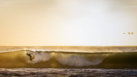 Surfer catching waves at sunset