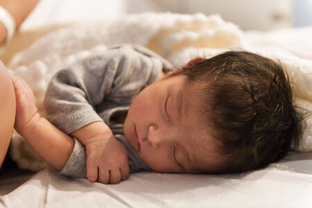 Newborn sleeping her first night while touching the knee of her mom