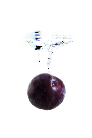 plum on white background falling and splashing water, giving a unique feeling of freshness and vitalityの写真素材
