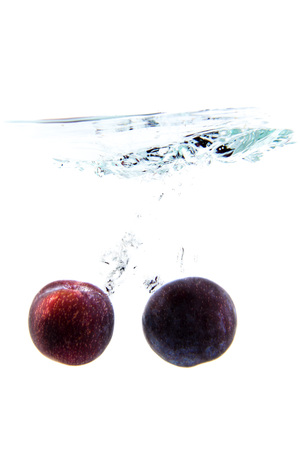 plum on white background falling and splashing water, giving a unique feeling of freshness and vitalityの写真素材