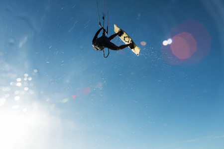 A surfer flying and splashing the water in front of the sun passing over the cameraの写真素材