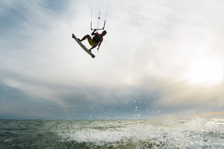 Surfer flying over the water with the sunset at the backgroundの写真素材
