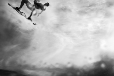 a black and white abstract image of a surfer flying through the sky passing over the camera