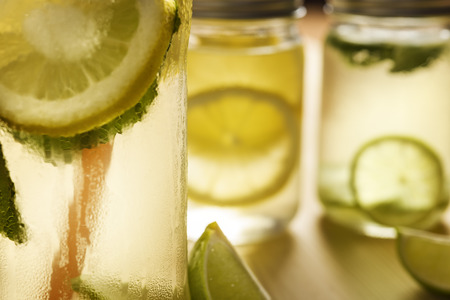 close-up of an iced lemonade with an unfocused background of two glass jars with lid on a wooden...