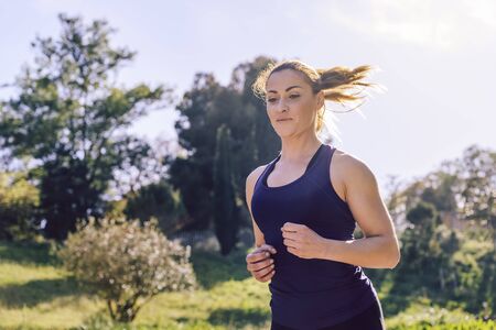 happy beautiful sports woman running during outdoor workout at the park at the morning with sunlight, sport and healthy lifestyle conceptの写真素材
