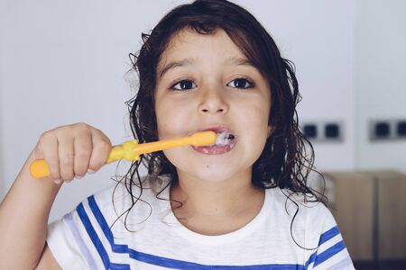 portrait of a little girl brushing her teeth in the bathroom before going to bed after taking a shower, kids hygiene conceptの写真素材