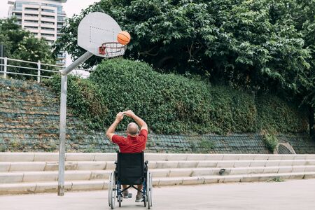 handicapped man playing basketball alone in the city, concept of adaptive sports and physical activity, rehabilitation for people with physical disabilitiesの写真素材