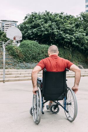 disabled man in wheelchair playing basketball on the court, concept of adaptive sports and physical activity, rehabilitation for people with physical disabilities, vertical photoの写真素材
