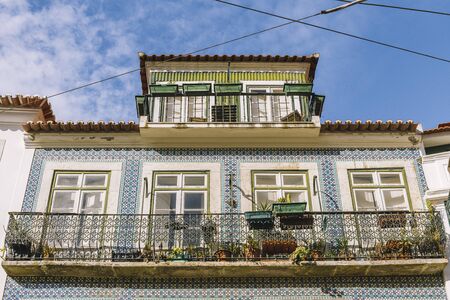 old tiled facade with windows and balcony of historic vintage house with geometric pattern at Lisbon, Portugalの写真素材