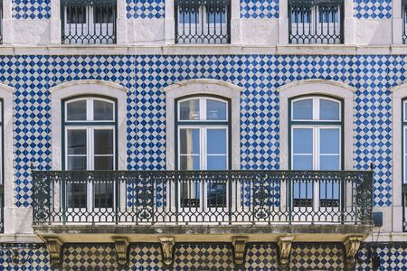 typical historic vintage house facade with windows and balcony in an old tile facade with geometric pattern, picturesque architecture at Lisbon, Portugalの写真素材