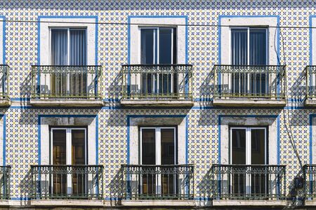 typical vintage tile facade of a portuguese building with windows, balconies and tiles with geometric pattern, picturesque architecture at Lisbon, Portugalの写真素材