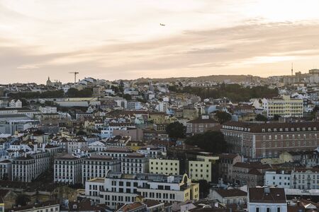 panoramic view of Lisbon houses with red roof tiles from Sao Jorge Castle at sunset, an airplane is flying over at the background, tourists spots in Portugalの写真素材