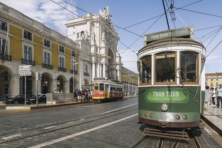 Lisbon, Portugal august, 2019: old vintage touristic tram passing by the typical cobblestone street in front of Augusta triumph arch street in a summer dayのeditorial素材