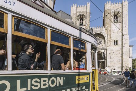 Lisbon, Portugal august, 2019: tourists by tram passing in front of the cathedral at Alfama districtのeditorial素材