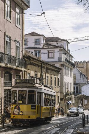 Lisbon, Portugal august, 2019: vertical photo of a yellow tourist tram through the narrow cobblestone streets of the touristic Alfama districtのeditorial素材