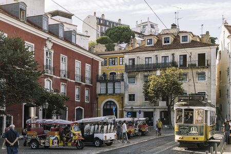 Lisbon, Portugal august, 2019: typical yellow tram and tuk tuk for tourists in a cobblestone square in Alfama districtのeditorial素材