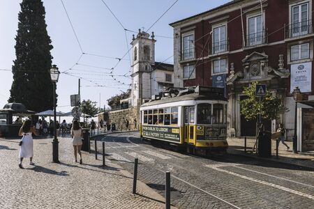Lisbon, Portugal august, 2019: typical yellow tram in the cobblestone square of Doors on Sol viewpoint in Alfama districtのeditorial素材