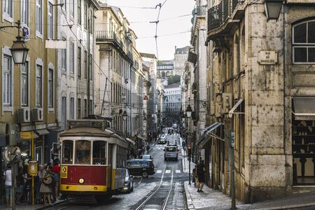 Lisbon, Portugal August, 2019: Tourists boarding the tram on a typical narrow cobblestone street in Alfama districtのeditorial素材