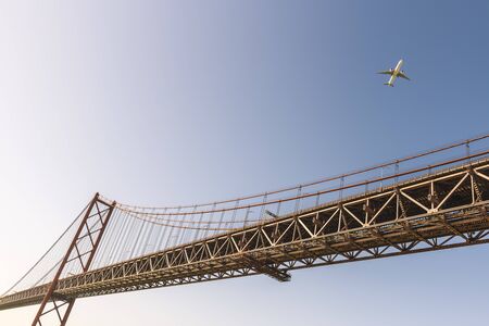 view of the 25 de Abril (25 April) suspension bridge over the Tagus river in Lisbon with an airplane...