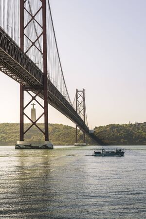 vertical view of 25 April bridge over Tagus river and Cristo Rei (Christ the King) monument in...