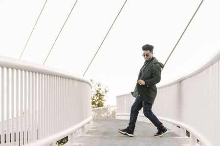 young stylish black man with white earphones and sun glasses dancing happy outdoor in the city and having some fun, lifestyle and technology concept, copy space for textの写真素材