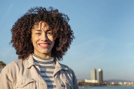 portrait of a beautiful young black woman smiling with curly afro hair in front of the Barcelona...