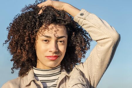 portrait of a beautiful young black woman smiling and touching her curly afro hair, concept of...