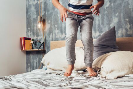 detail of a little girl legs jumping on her parents bed, home lifestyle concept and happy childhoodの写真素材
