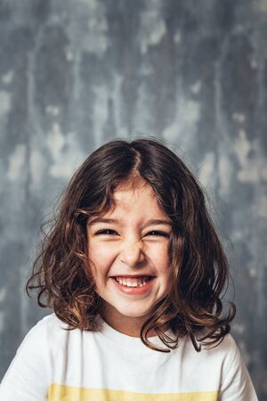 vertical portrait of a happy little girl smiling on a blue background, happy childhood and lifestyle...