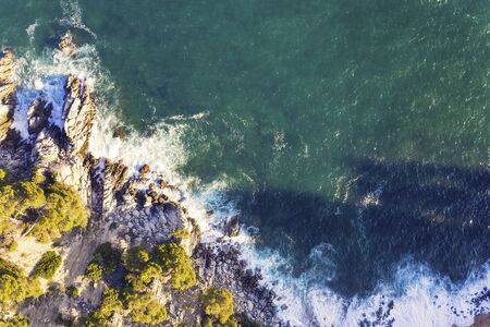 aerial top view of ocean beautiful sea waves crashing on the rocky island coast with spray and foam, concept of adventure lifestyle and summer holidays in the wildernessの写真素材