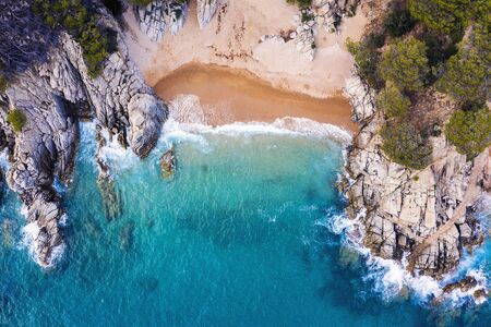 top view of a cove of turquoise waters surrounded with rock sea cliffs covered with trees and...